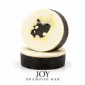 Loveyemmaskincare Joy Shampoo Bar placed on a surface, showcasing its rectangular shape and natural packaging.