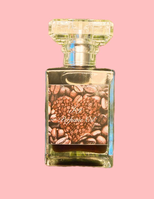 Joy Perfume Oil by LOVEBYEMMASKINCARE with sweet coffee and cardamom scent, featuring a glass bottle with a dropper and gold accents.